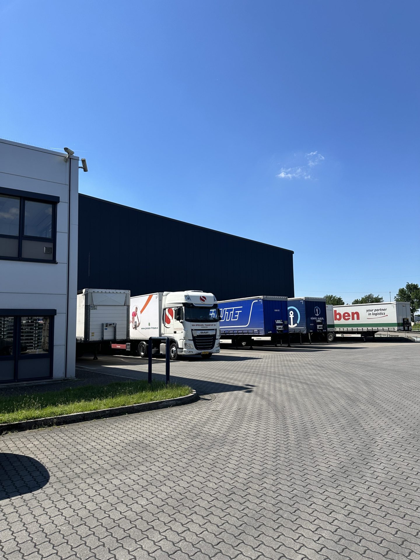 Sattelzug und Auflieger verschiedener Speditionen entlang der Lagerhalle in Hünxe