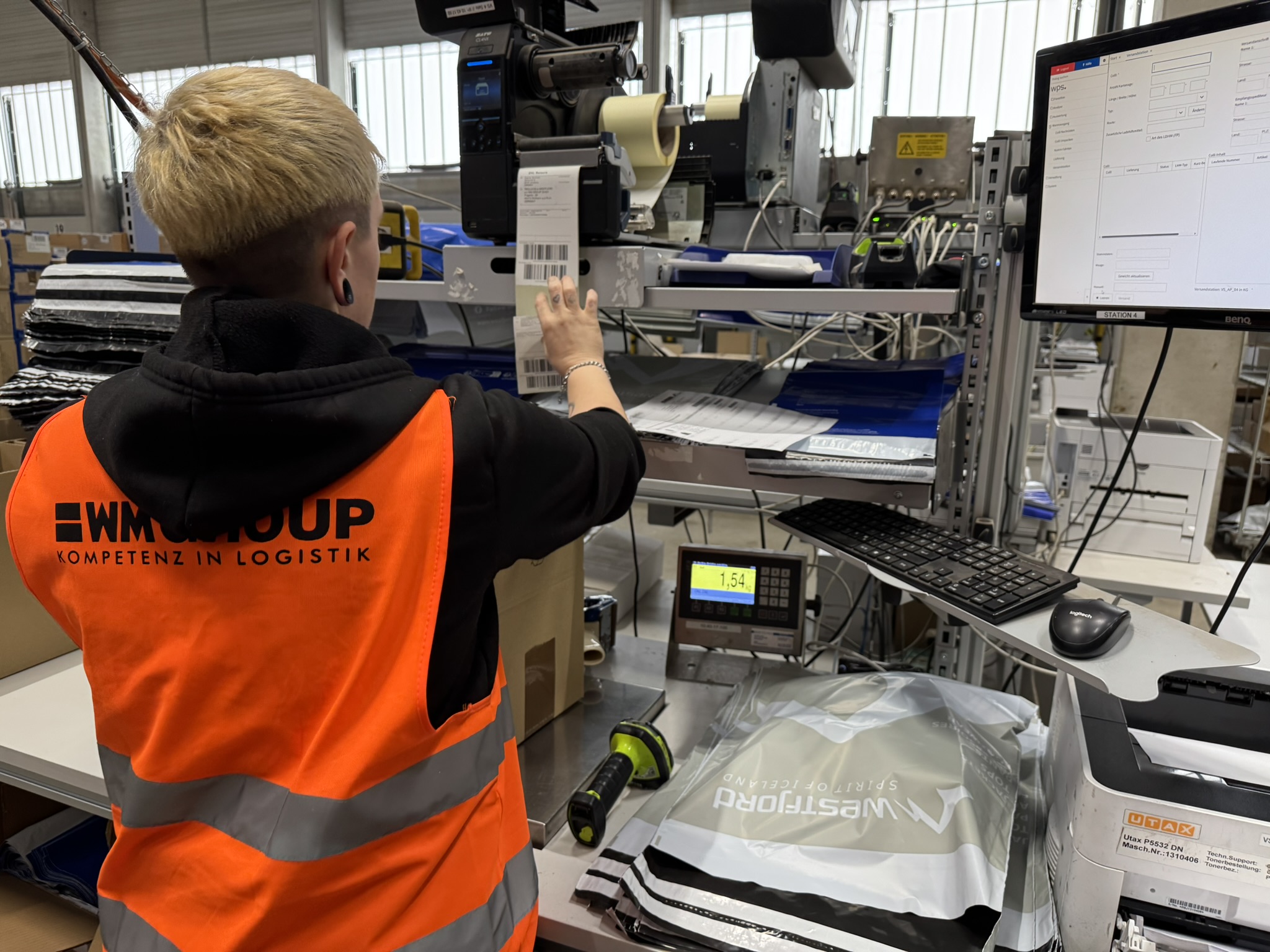 WM-GROUP-Mitarbeiterin an der Versandstation beim Etikettieren eines Pakets