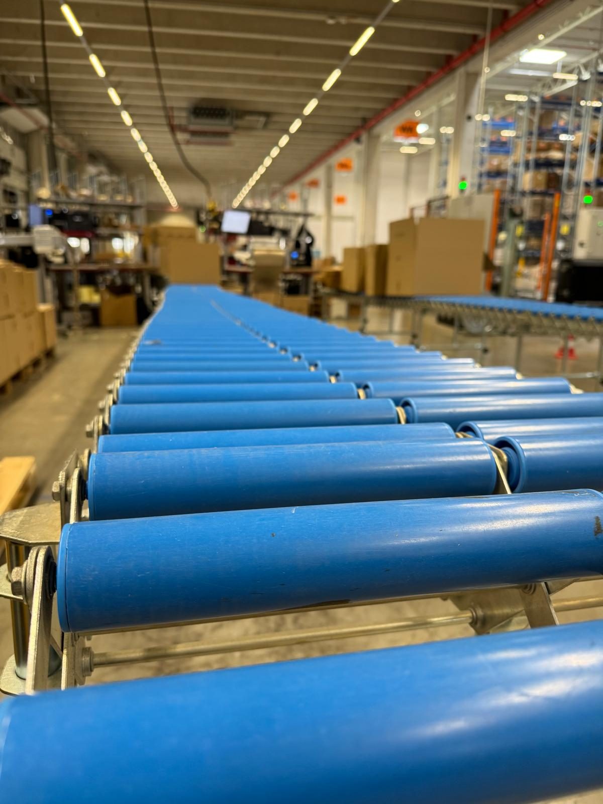 Blaue Rollenförderstrecke, die durch den Versandbereich zu den Packplätzen führt.
